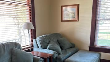 A living room with a sectional sofa, ottoman, and a small wooden table.