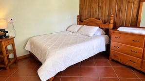 Une chambre à coucher avec un lit, une tête de lit en bois, une table de chevet, une lampe et une commode.