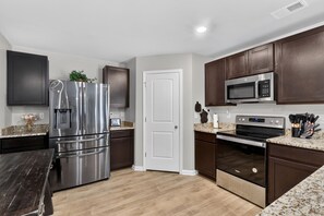 A modern kitchen with stainless steel appliances, dark wooden cabinets, and a granite countertop. - Beautiful 5-bedroom house with all the amenities and convenient location. (Ellenwood)