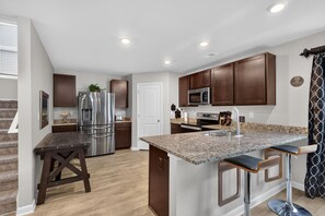 A modern kitchen with stainless steel appliances, a granite countertop, and dark wooden cabinets. - Beautiful 5-bedroom house with all the amenities and convenient location. (Ellenwood)