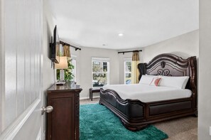 A bedroom with a large bed, a dresser, a nightstand, and a window with curtains. - Beautiful 5-bedroom house with all the amenities and convenient location. (Ellenwood)