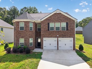 A two-story brick house with a garage, a front yard, and a neighboring house. - Beautiful 5-bedroom house with all the amenities and convenient location. (Ellenwood)