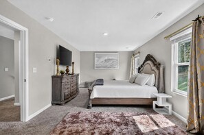 A bedroom with a large bed, a dresser, a TV, and a window with curtains. - Beautiful 5-bedroom house with all the amenities and convenient location. (Ellenwood)
