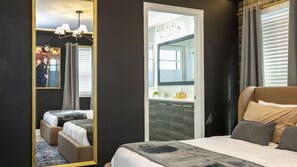 Une chambre d’hôtel avec un grand lit, un coin salon séparé, une salle de bain avec un miroir et une vue sur l’extérieur.