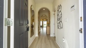 Un couloir doté d’un plancher en bois, d’une porte avec une poignée argentée et d’un luminaire fixé au mur.