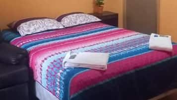 A bedroom with a bed, a bedside table, a chair, and a small plant.