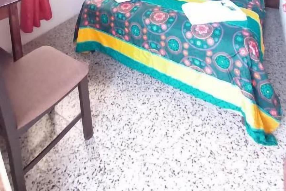 Un dormitori amb llit de fusta, escriptori i una cadira.