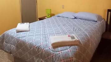 Een hotelkamer met een bed, een schilderij aan de muur en een deur.