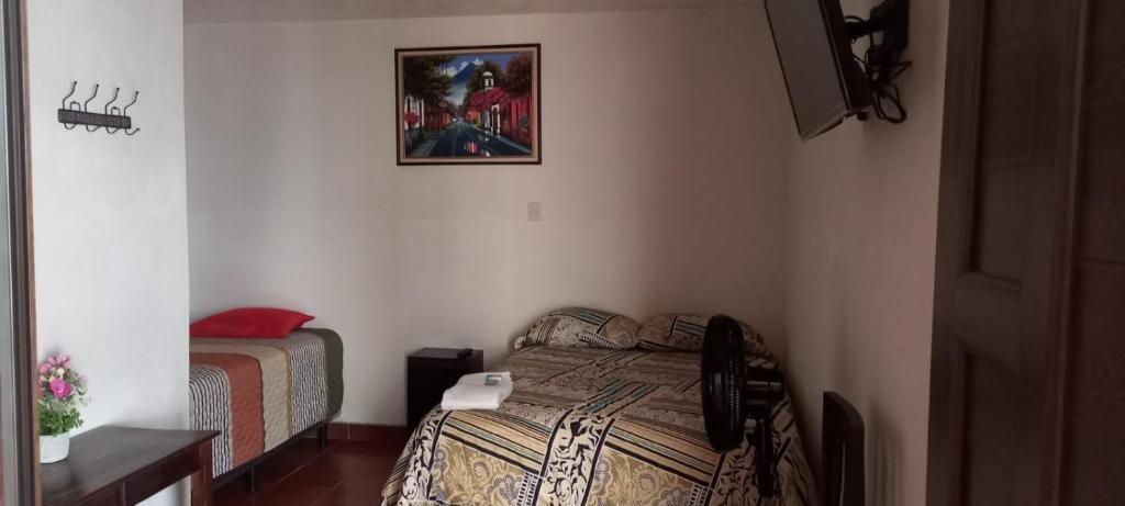 Un dormitorio con una cama, una mesita de noche, una lámpara, un cuadro en la pared y una puerta.