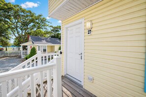 A yellow building with a white door and a mailbox marked with the number 27. - Parrot Bay Townhouse 27 | Pet Friendly (Ocean City)