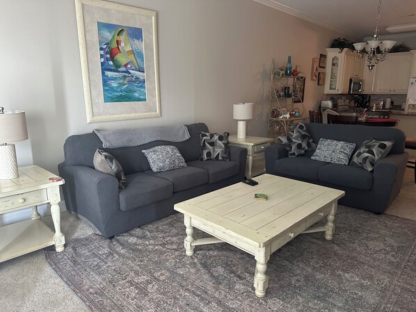 A living room with two sofas, a coffee table, and a painting of sailboats.
