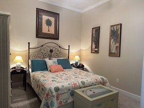 A bedroom with a bed, two bedside lamps, a nightstand, a dresser, and two framed pictures on the wall.