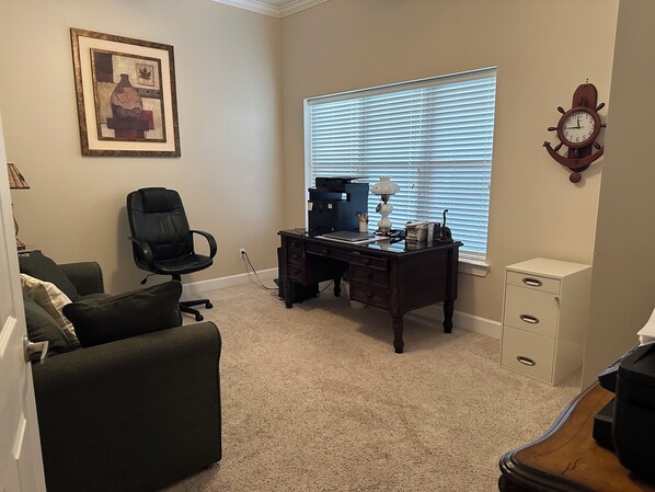 A room with a desk, chair, and a window with blinds.