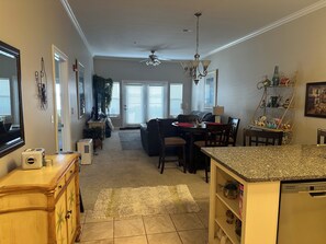 A spacious living area with a dining table, chairs, a sofa, and a kitchen area with a dishwasher.