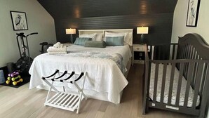 Quarto com cama, mesas de cabeceira, berço, ventilador e equipamentos de exercícios.