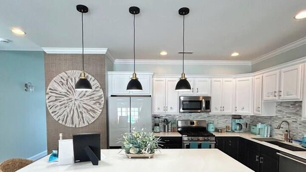 Cozinha moderna com ilha central, iluminação pendente e um grande painel decorativo.