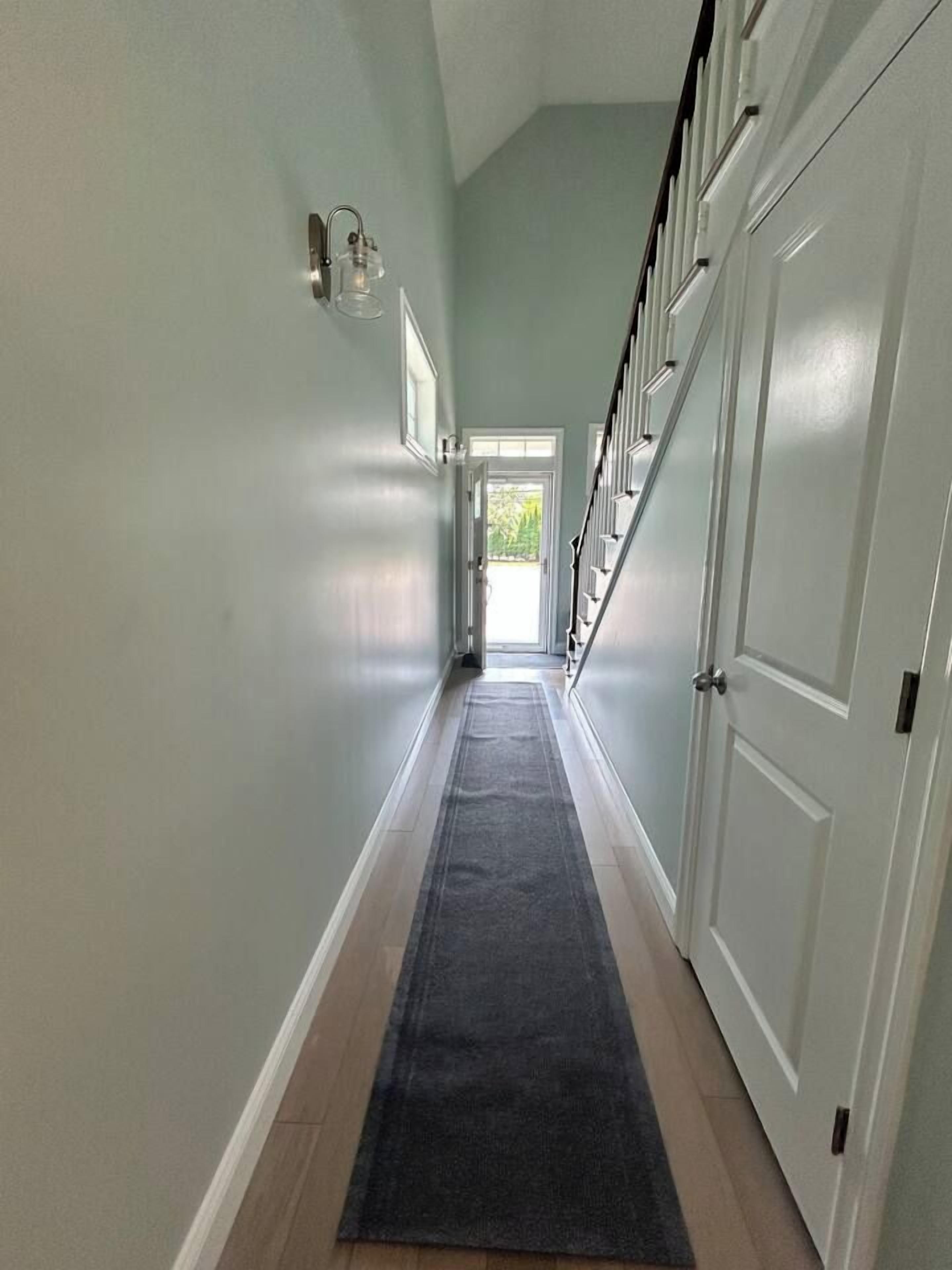 A hallway with a carpet, a door, and a staircase.