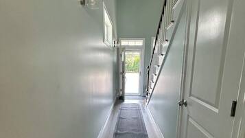 A hallway with a carpet, a door, and a staircase.