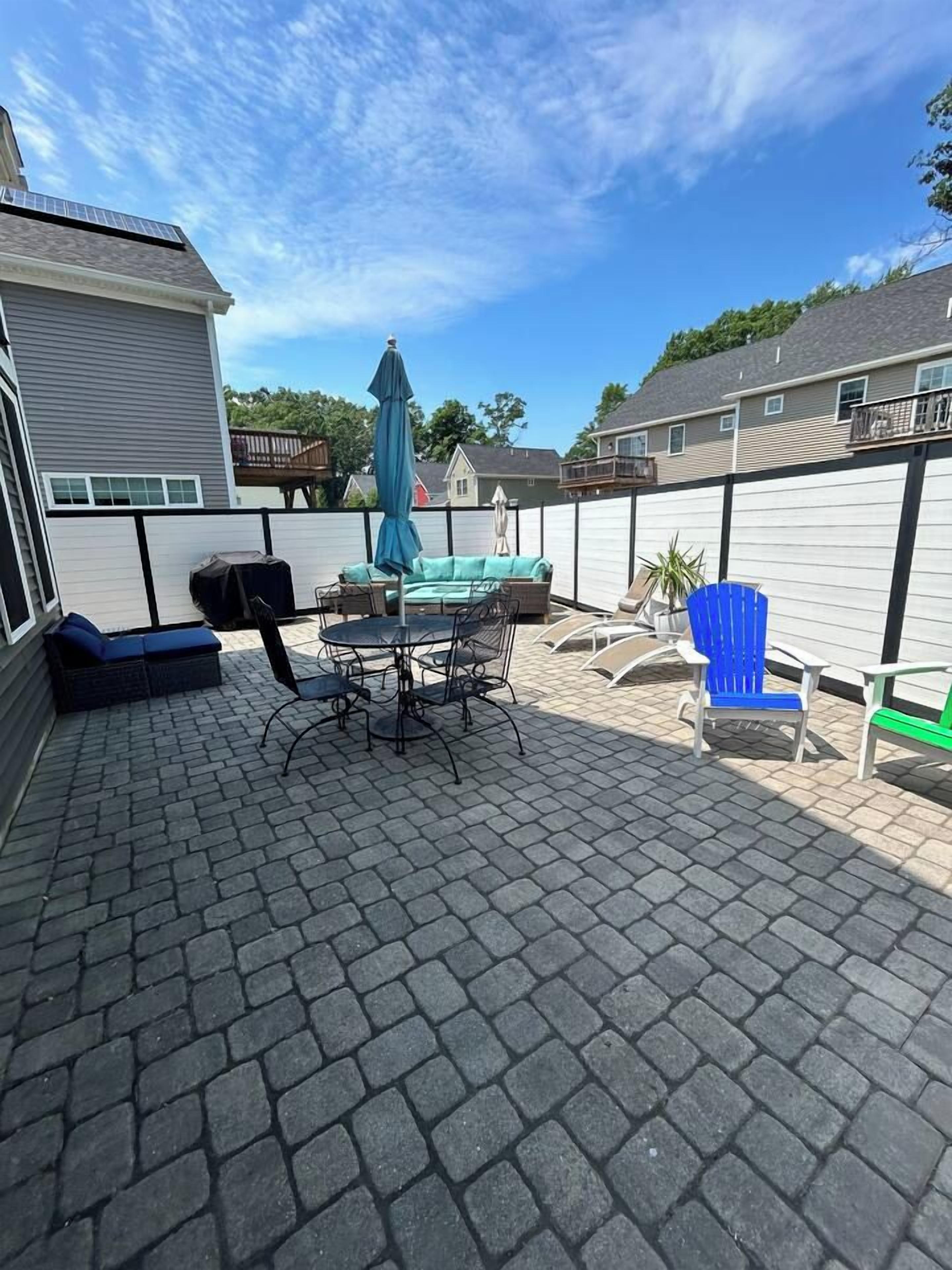 Eine Terrasse mit Tisch und Stühlen, ein blauer Stuhl und eine grüne Bank.