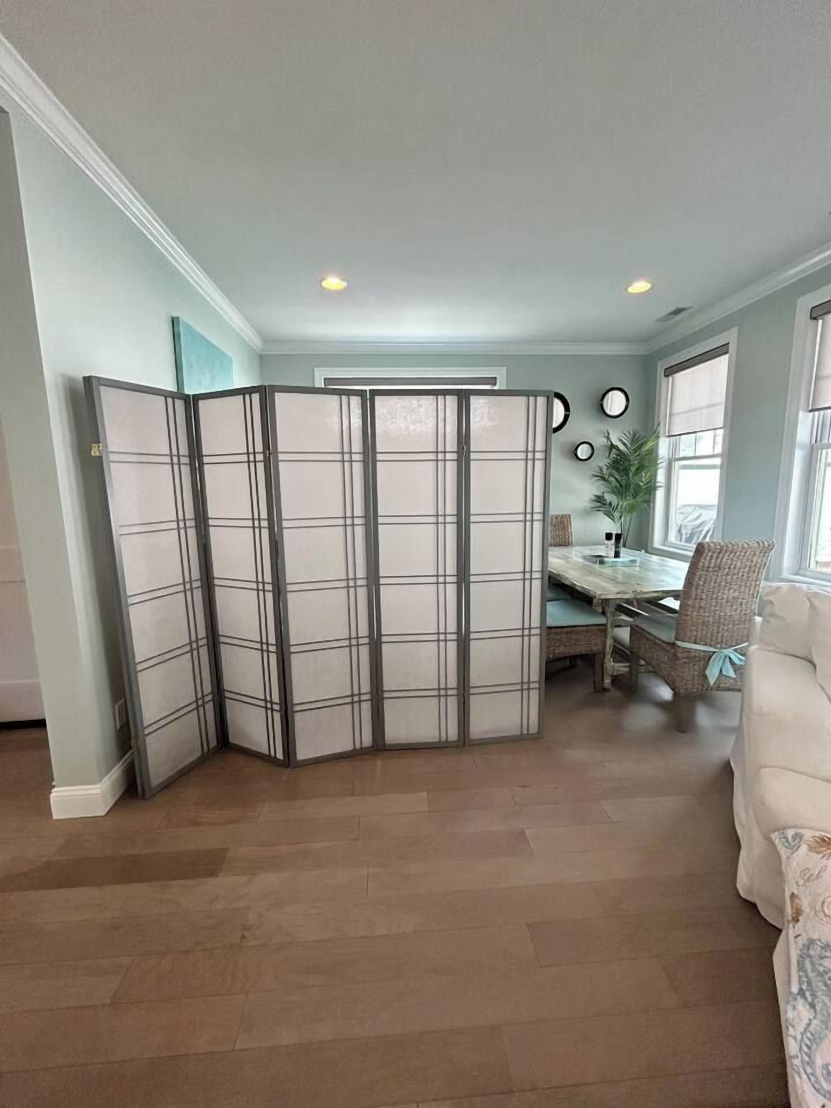 A room with a sectional sofa, a dining table with chairs, and a large window.