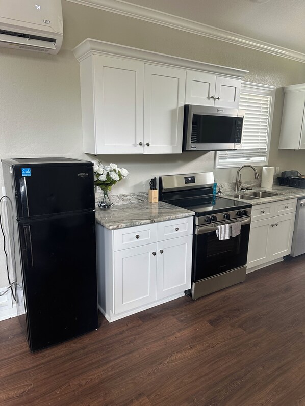 A kitchen with white cabinets, a black refrigerator, a microwave, a stove, and a dishwasher.