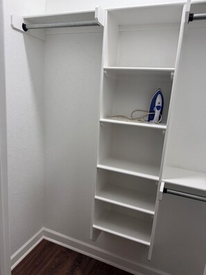 A white closet with open shelves and a hanging rod.