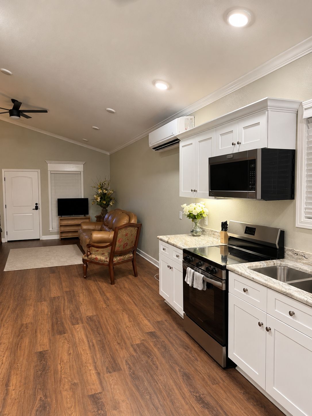 A kitchen with white cabinetry, a black microwave, and a stainless steel stove.