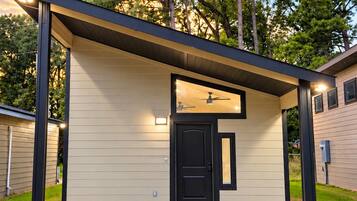 A modern building with a flat roof, a black door, and a gravel driveway.