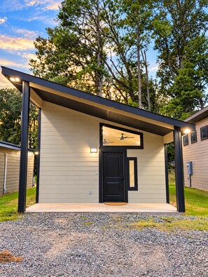 A modern building with a flat roof, a black door, and a gravel driveway.