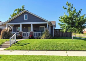 A single-story house with a front porch, a small front yard, and a wooden fence.