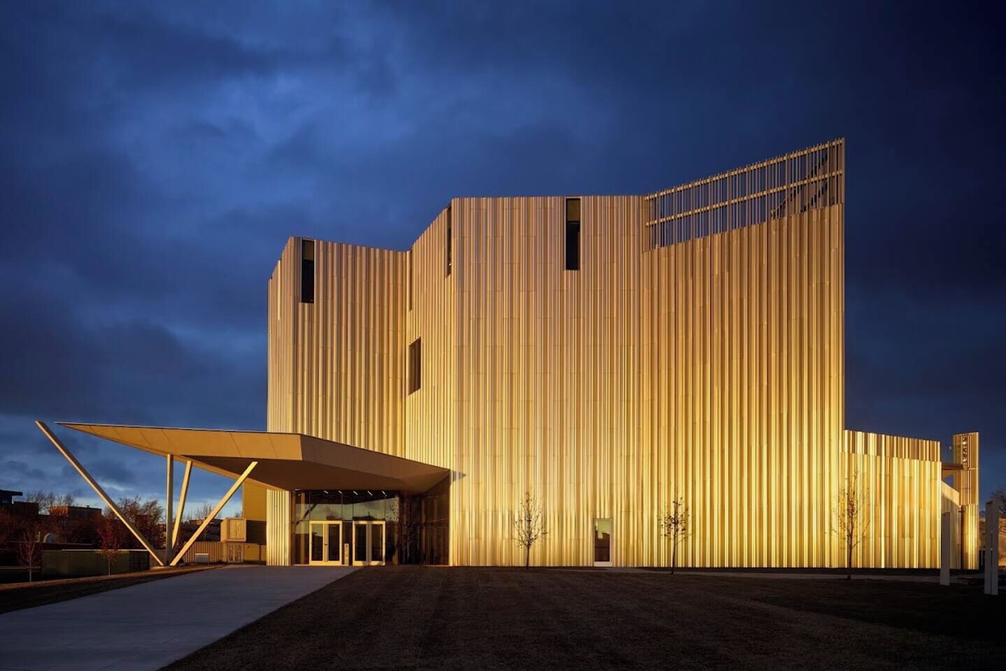 Un edificio moderno con fachada de madera vertical distintiva, un acceso cubierto y un techo plano.