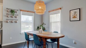 A dining area with a wooden table, blue chairs, a hanging light fixture, and a wall-mounted plant. - Best Value, Sleeps 6, Near Downtown & Bricktown (Oklahoma City)