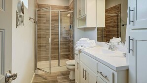 A modern bathroom with a glass-enclosed shower, a white sink, and a large mirror. - Best Value, Sleeps 6, Near Downtown & Bricktown (Oklahoma City)