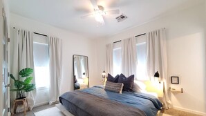 A bedroom with a bed, curtains, a ceiling fan, a mirror, and a bedside lamp. - Best Value, Sleeps 6, Near Downtown & Bricktown (Oklahoma City)