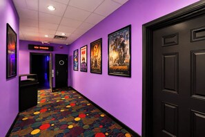 Ein Flur mit violetten Wänden, einem gemusterten Teppich und Filmplakaten.