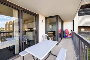 Ein Balkon mit Tisch und Stühlen, eine Schiebetür, die zu einem Zimmer führt, und Blick auf die Straße.