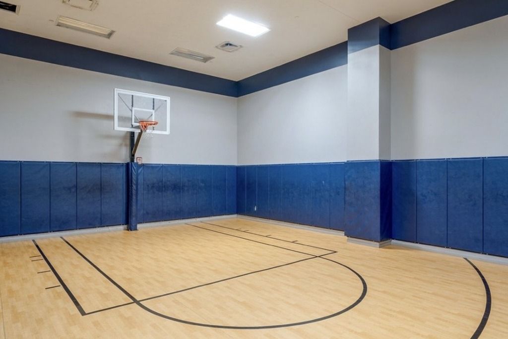 Un terrain de basket-ball intérieur équipé d’un panier, doté d’un plancher en bois et dont les murs sont peints en bleu et en blanc.