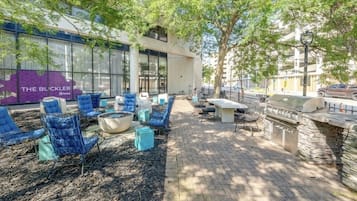 Un espace extérieur aménagé avec des chaises bleues et un barbecue en pierre.