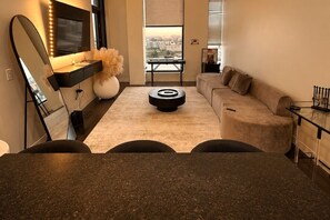 A modern living room with a sofa, a coffee table, and a TV with a mirror above it.