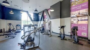 A gym with various exercise equipment, including treadmills, elliptical machines, and weight machines.