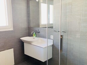 Ein modernes Badezimmer mit Waschbecken, Spiegel und Duschkabine.