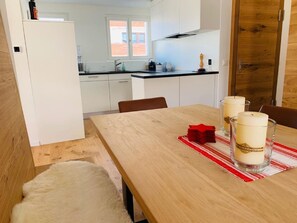 Cozinha moderna com armários brancos, mesa de jantar de madeira e um jogo americano xadrez vermelho e branco.
