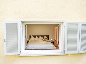 Ein Hotelzimmer mit Bett, Kissen, Nachttisch und einem Tisch mit Lampe.