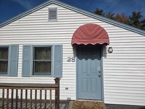 A white house with a blue door, number 28, and a red awning. - Amazing 1-bedroom Condo with AC in cozy Saco (Saco)