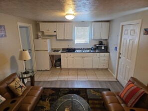 A compact living space with a kitchenette, a glass coffee table, and two leather sofas. - Amazing 1-bedroom Condo with AC in cozy Saco (Saco)