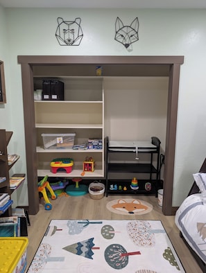 Una habitación infantil con una estantería, un escritorio y una cama.