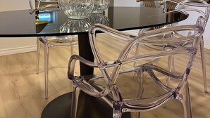 Un comedor con una mesa de vidrio, sillas transparentes y un centro de mesa decorativo de cristal.