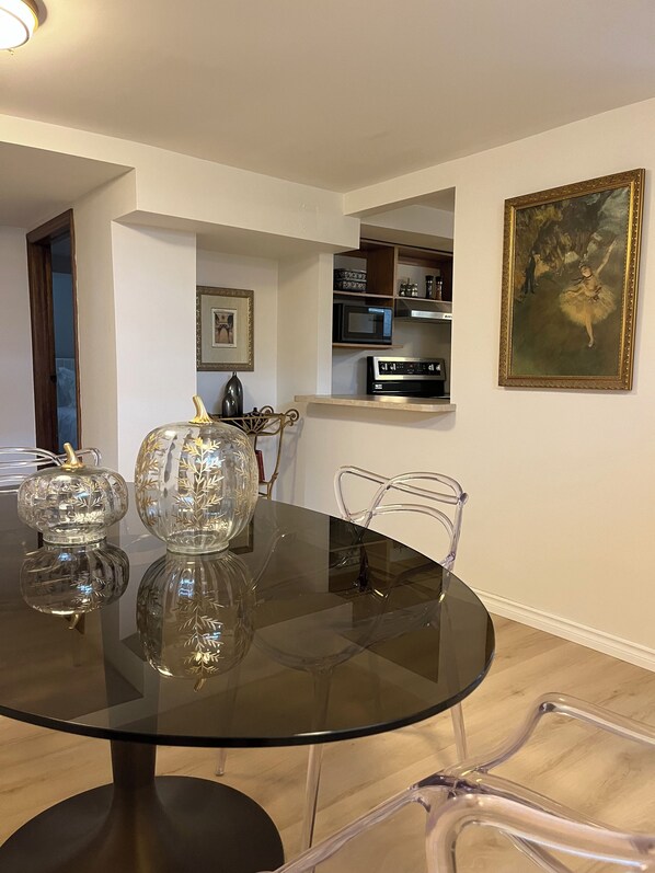 A dining area with a round glass table, clear chairs, and decorative glass vases.