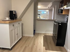 A kitchen with a coffee maker, microwave, and refrigerator.