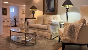 Una sala de estar con sofá, sillones, una mesa de centro y dos lámparas.